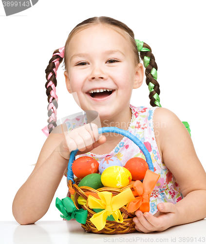 Image of Little girl with basket full of colorful eggs