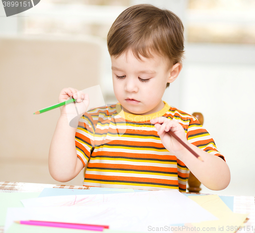 Image of Little boy is drawing on white paper