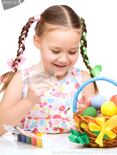 Image of Little girl is painting eggs preparing for Easter