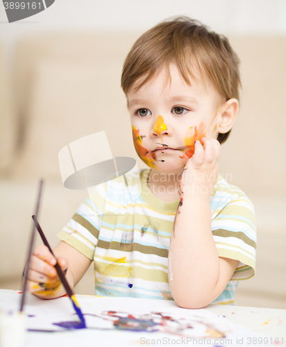 Image of Little boy is playing with paints