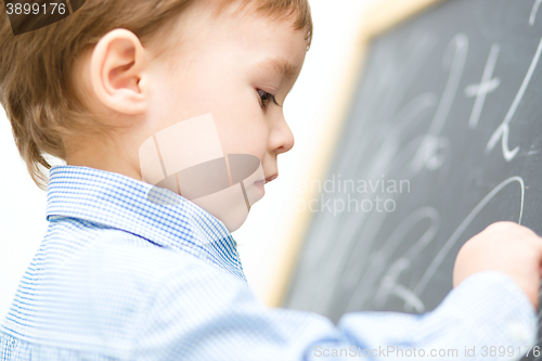 Image of Little boy is writing on blackboard
