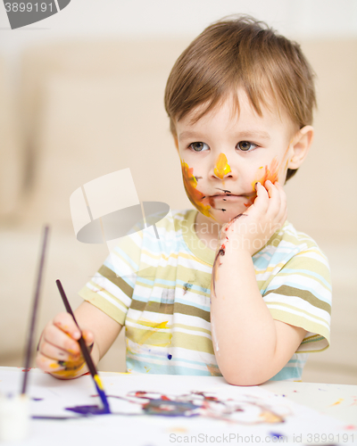 Image of Little boy is playing with paints