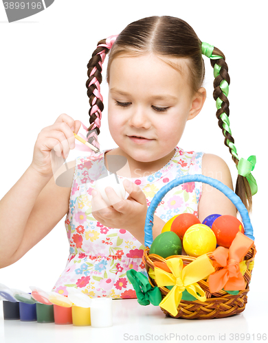 Image of Little girl is painting eggs preparing for Easter