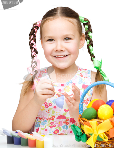 Image of Little girl is painting eggs preparing for Easter