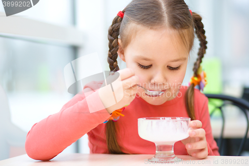 Image of Little girl is eating ice-cream in parlor