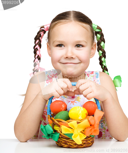 Image of Little girl with basket full of colorful eggs