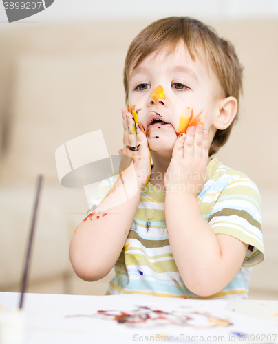 Image of Little boy is playing with paints