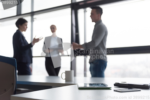 Image of close up of tablet, business people on meeting in background