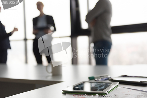 Image of close up of tablet, business people on meeting in background