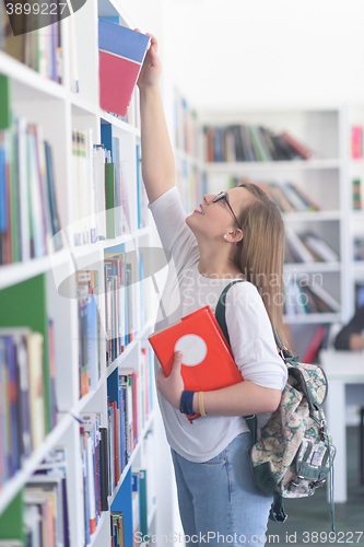 Image of famale student selecting book to read in library