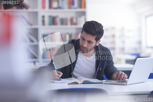 Image of student in school library using laptop for research