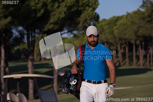 Image of golfer  walking and carrying golf  bag