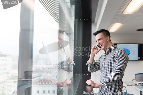 Image of young business man speaking on  smart phone at office