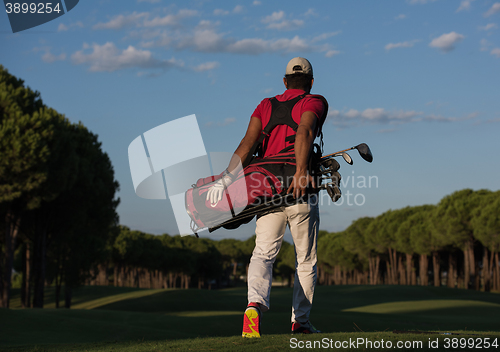 Image of golfer  walking and carrying golf  bag