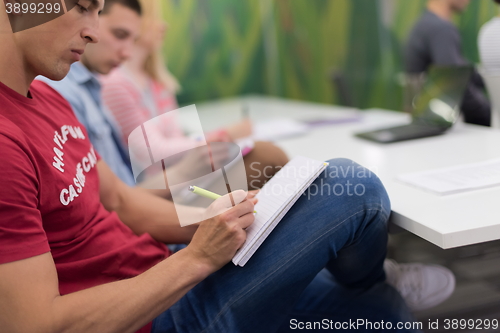 Image of male student taking notes in classroom