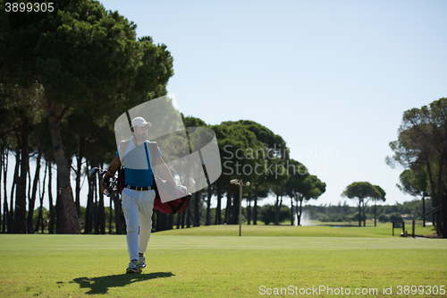 Image of golf player walking and carrying bag