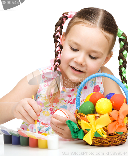 Image of Little girl is painting eggs preparing for Easter