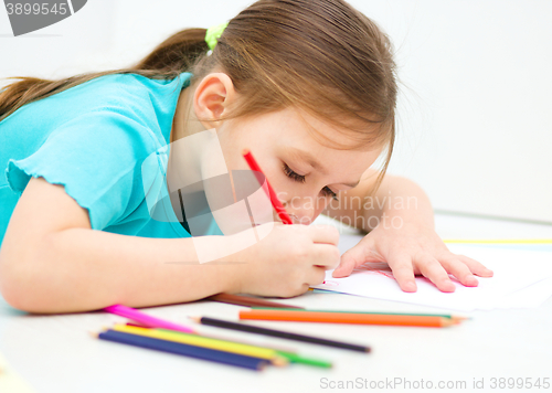 Image of Little girl is drawing using pencils