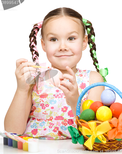 Image of Little girl is painting eggs preparing for Easter