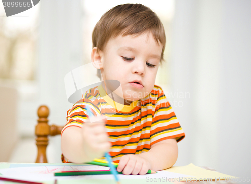 Image of Little boy is drawing on white paper