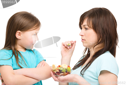 Image of Mother is trying to feed her daughter