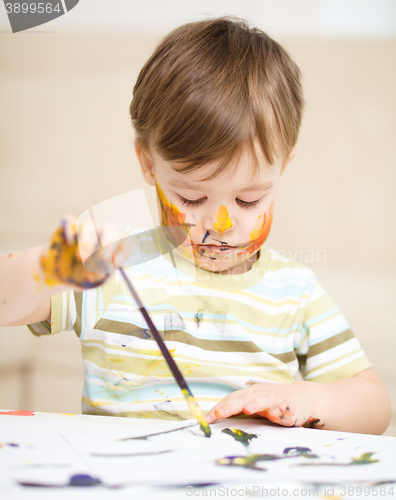 Image of Little boy is playing with paints