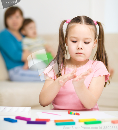 Image of Little girl is playing with plasticine