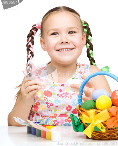 Image of Little girl is painting eggs preparing for Easter