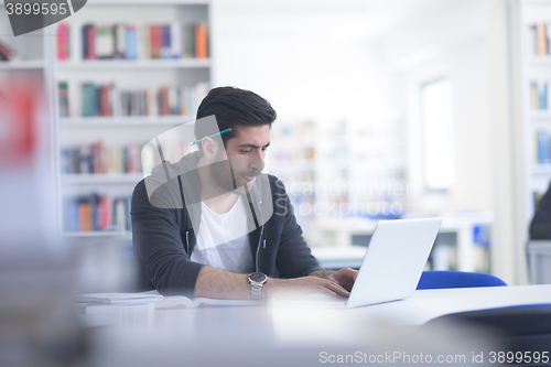 Image of student in school library using laptop for research