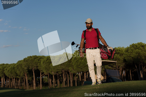 Image of golfer  walking and carrying golf  bag
