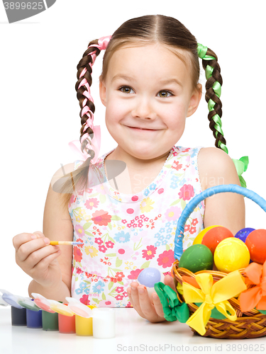 Image of Little girl is painting eggs preparing for Easter