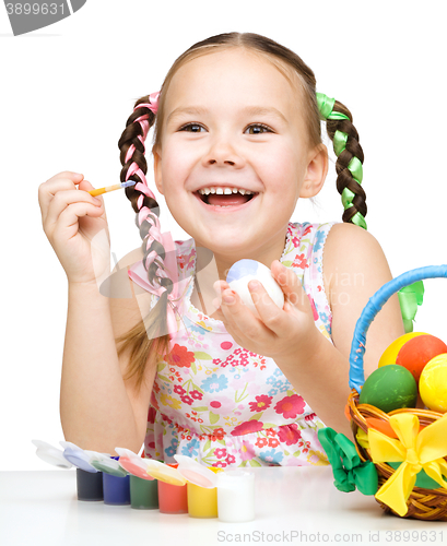 Image of Little girl is painting eggs preparing for Easter