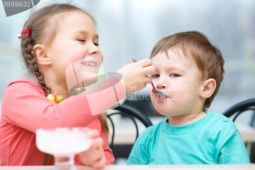 Image of Girl is feeding his little brother with ice-cream