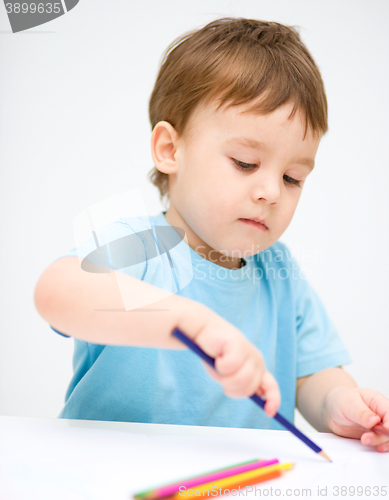 Image of Little boy is drawing on white paper