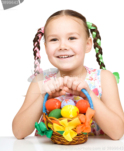 Image of Little girl with basket full of colorful eggs