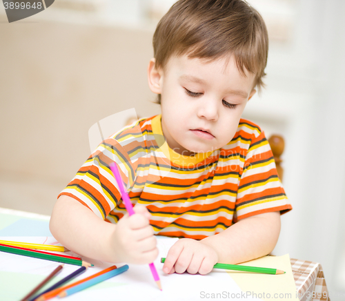 Image of Little boy is drawing on white paper