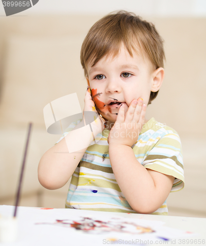 Image of Little boy is playing with paints