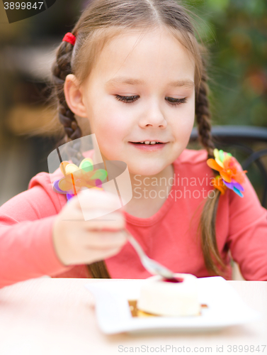 Image of Little girl is eating cake in parlor