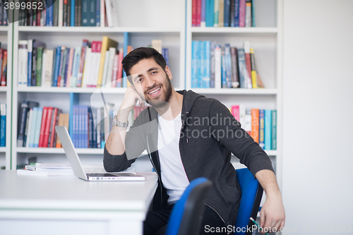 Image of student in school library using laptop for research