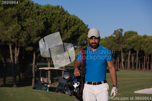 Image of golfer  walking and carrying golf  bag
