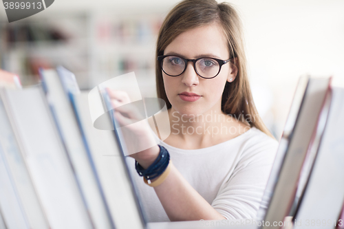 Image of portrait of famale student selecting book to read in library