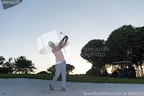 Image of golfer hitting a sand bunker shot on sunset