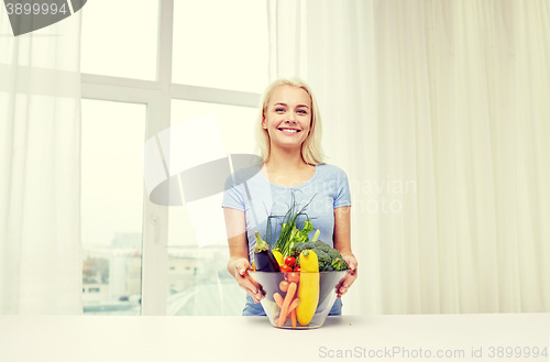 Image of smiling young woman cooking vegetables at home