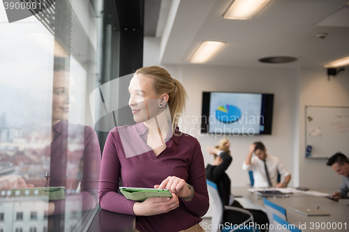 Image of blonde businesswoman working on tablet at office