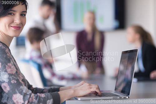 Image of young business woman at office working on laptop with team on me