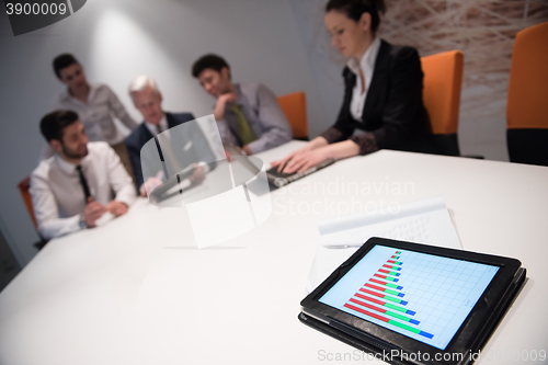 Image of close up of touchpad with analytics documents at business meetin