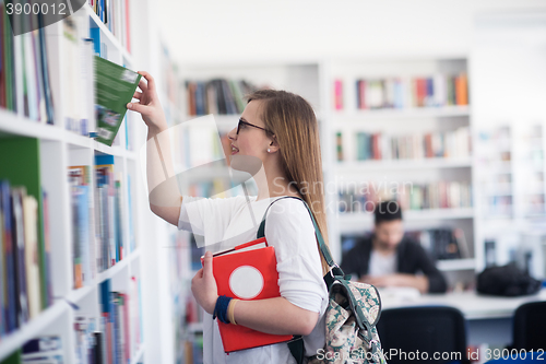 Image of famale student selecting book to read in library