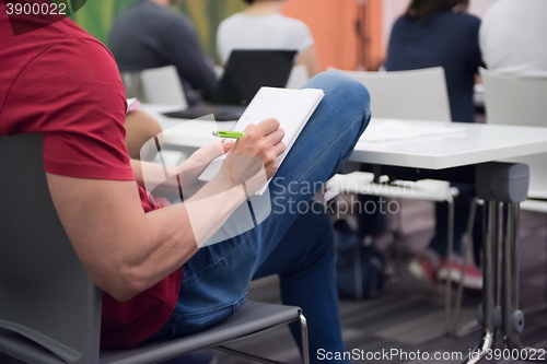 Image of male student taking notes in classroom