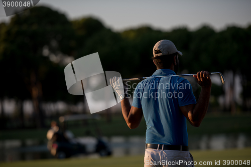 Image of golfer from back at course looking to hole in distance