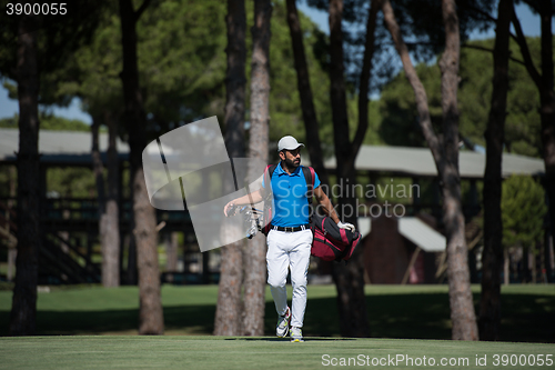 Image of golf player walking and carrying bag